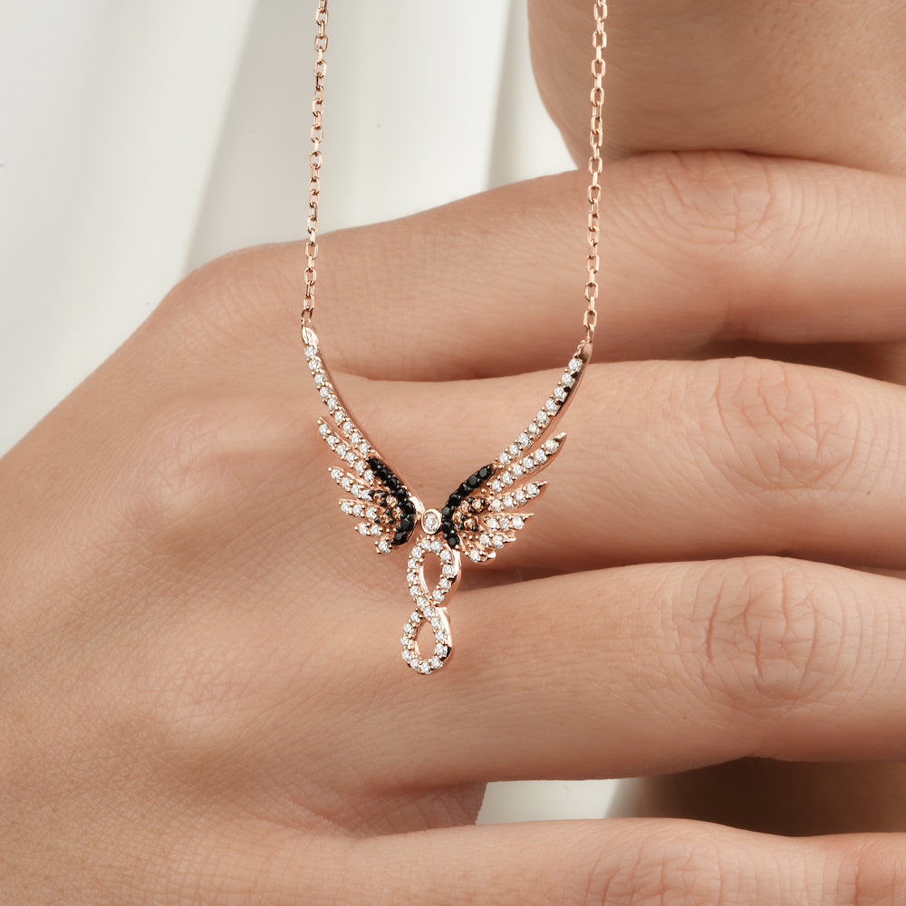 Rosévergoldete Infinity Angel Wings Halskette mit Zirkonia, locker über einer Hand liegend.