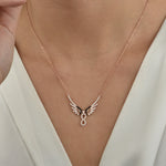 Infinity Angel Wings Halskette in Rosé getragen am Hals, elegantes Dekolleté in Weiß.