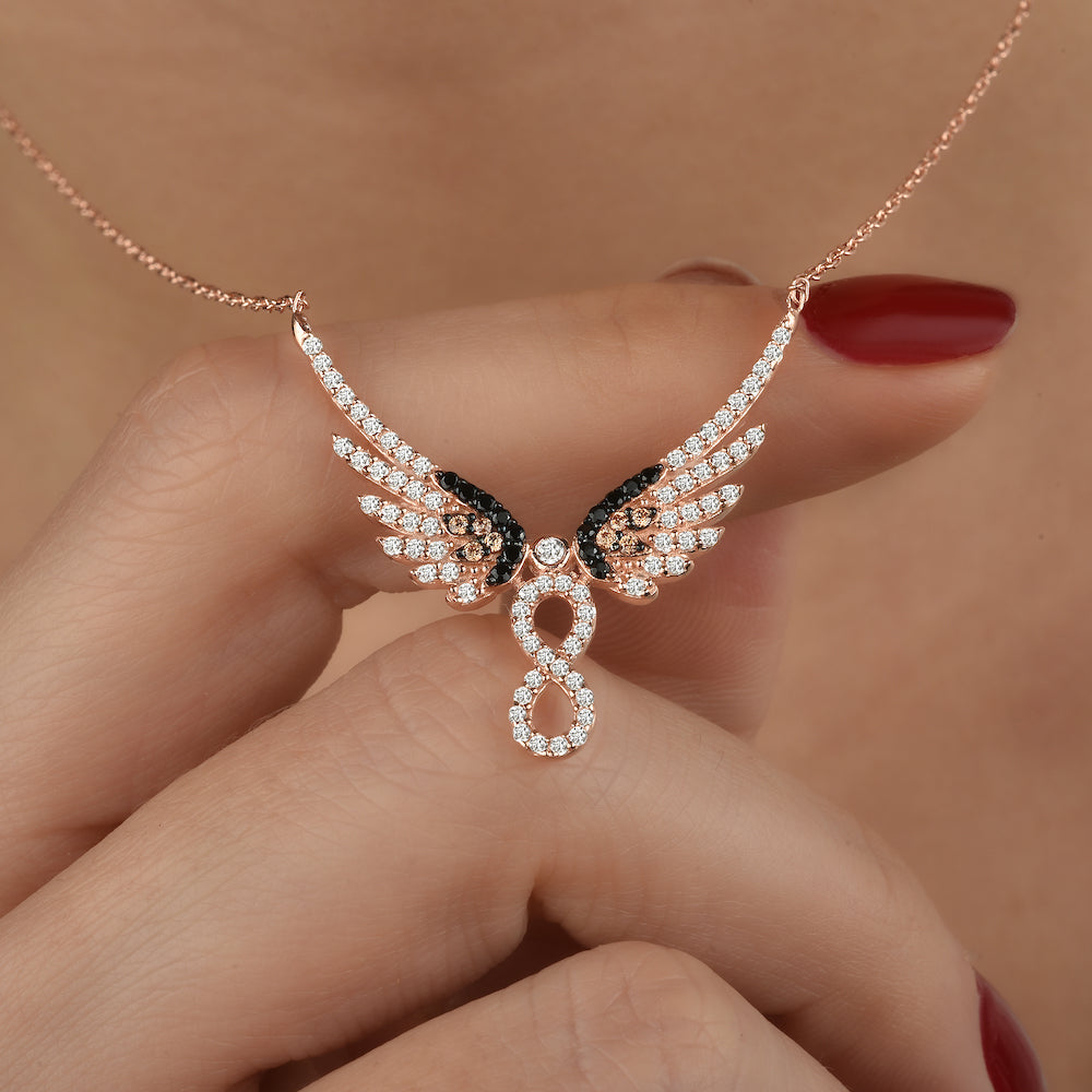 Hand hält Infinity Angel Wings Halskette in Rosé, funkelnder Anhänger mit Engelsflügeln.