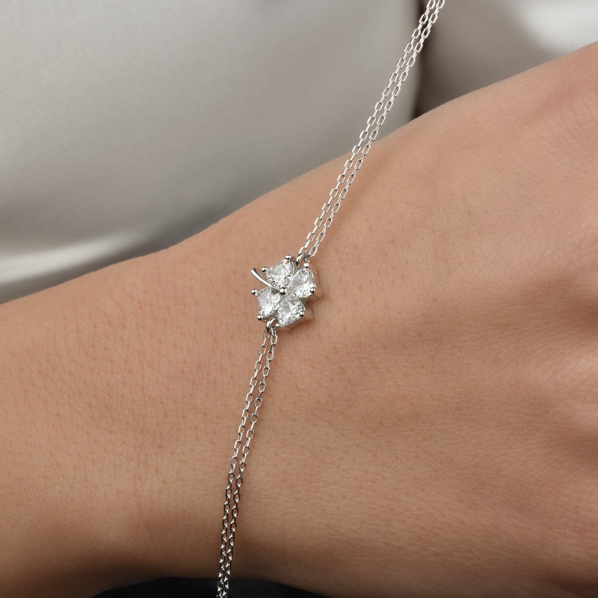 Kleeblatt Zirkonia Armkette Silber, getragen am Handgelenk, eleganter Damenschmuck mit Symbol für Glück