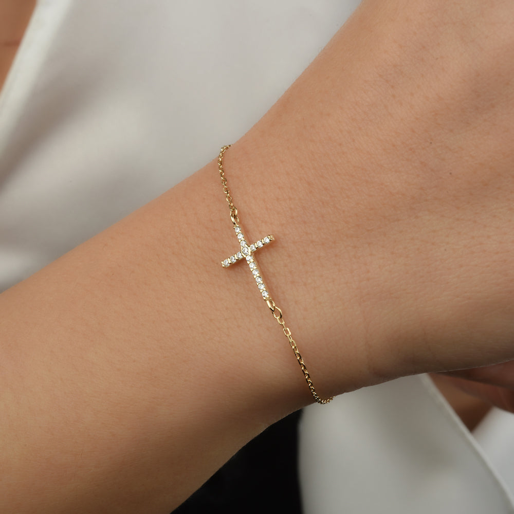 Goldenes Kreuz Armband mit Zirkonia am Handgelenk – zart und elegant.