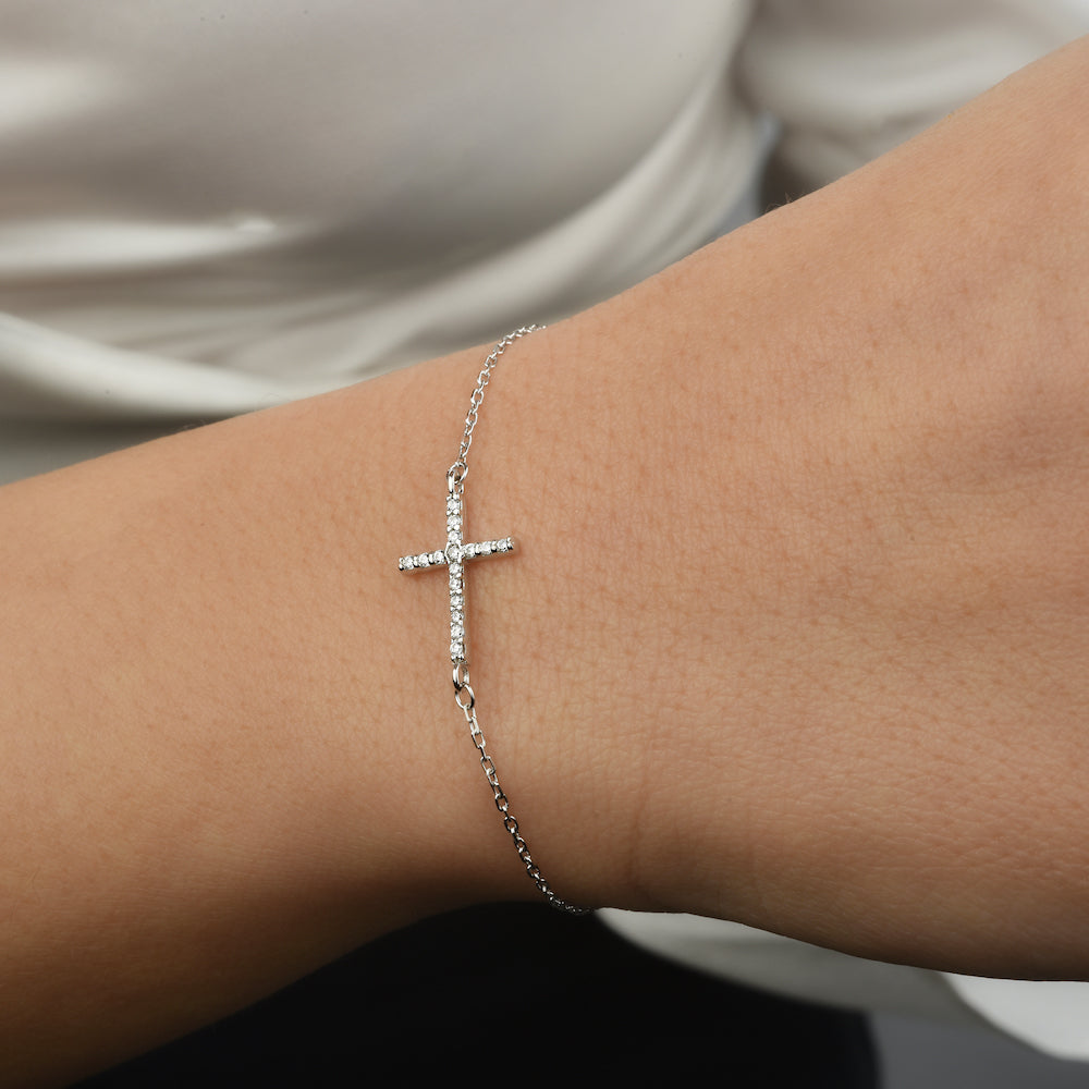 Nahaufnahme: filigrane Kreuz Armkette Silber mit Zirkonia, elegant am Handgelenk.