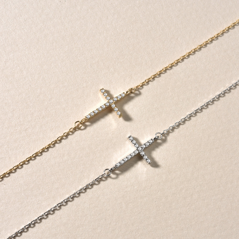 Vergleich: Kreuz Armkette mit Zirkonia in Gold und Silber auf hellem Hintergrund.