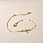 Kreuz Armkette Gold mit Zirkonia – Detailaufnahme auf hellem Hintergrund.