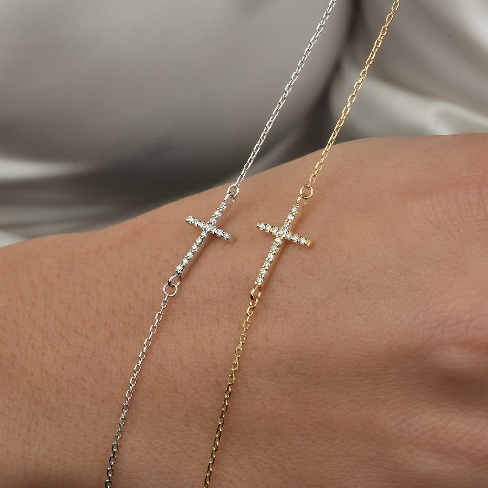 Zwei Kreuz Armbänder mit Zirkonia auf der Hand – Gold und Silber kombiniert.