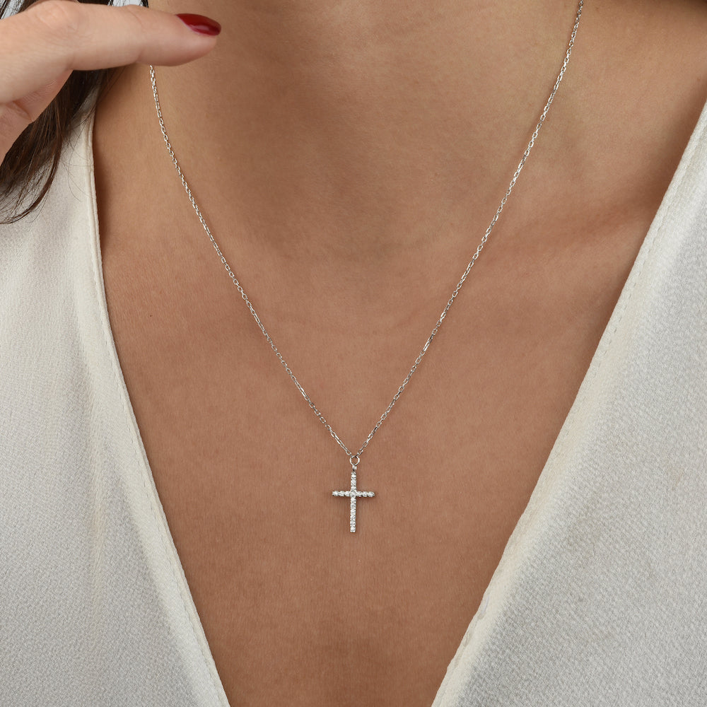 Silberne Kreuz Zirkonia Kette getragen am Hals einer Frau mit weißer Bluse.
