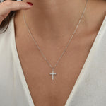 Silberne Kreuz Zirkonia Kette getragen am Hals einer Frau mit weißer Bluse.