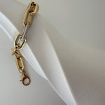 Goldenes Link Bracelet Armband mit Zirkonia an hellem Armreif-Display seitlich fotografiert.
