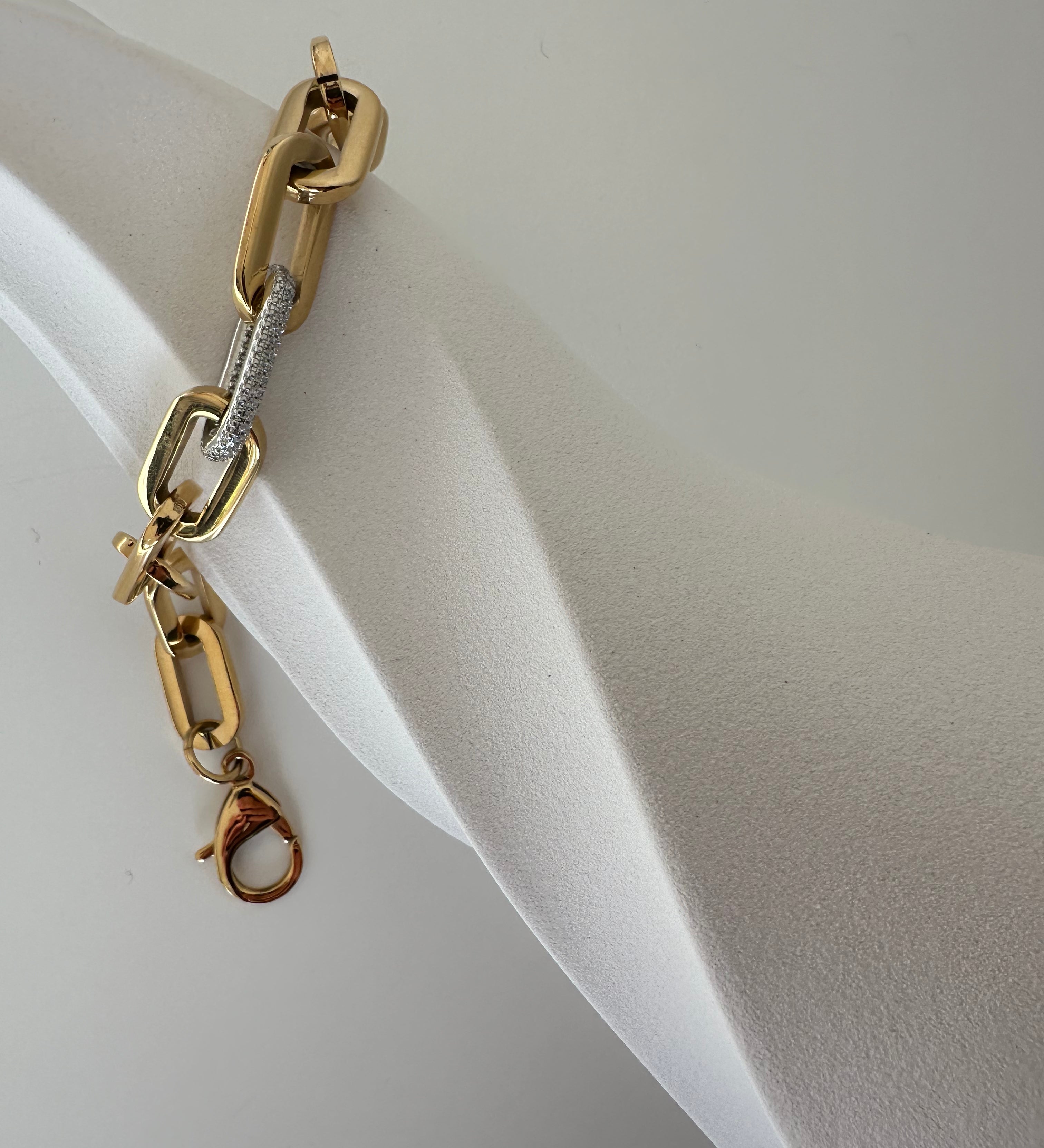 Goldenes Link Bracelet Armband mit Zirkonia an hellem Armreif-Display seitlich fotografiert.