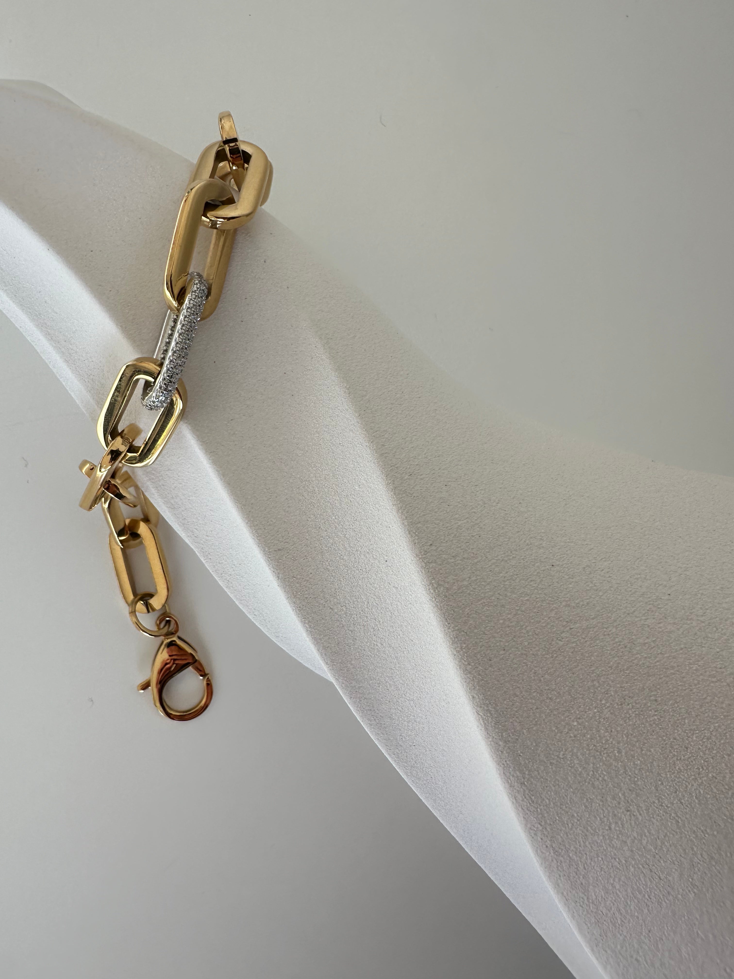 Goldenes Link Bracelet Armband mit Zirkonia an hellem Armreif-Display seitlich fotografiert.