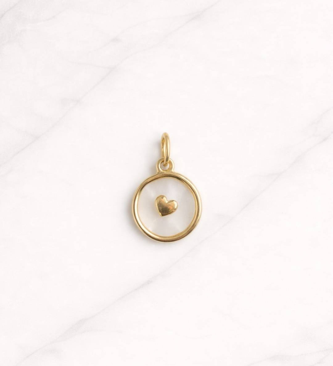 Lyon CHARM in Gold mit Herzdetail auf hellem Marmorhintergrund.