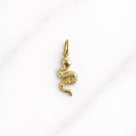 Goldener Marrakesh CHARM als filigraner Schlangenanhänger auf hellem Marmorhintergrund, Schmuck für Damen.