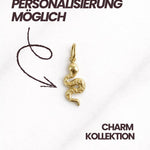 Eleganter Marrakesh CHARM Schlangenanhänger aus 18K vergoldetem Edelstahl, flach auf Marmor platziert.