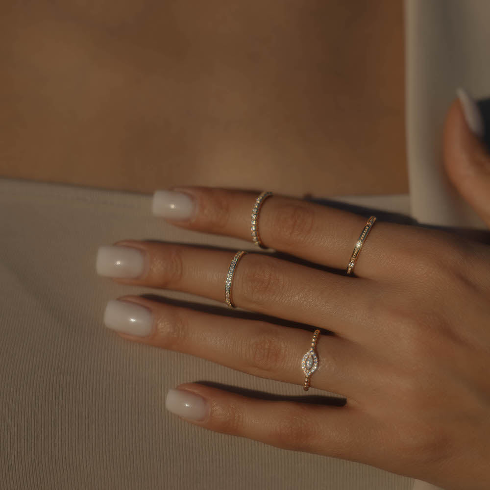 Gestapelte Goldringe an einer Hand, darunter der Memori Zirkonia Ring mit feinen Zirkonia.