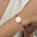 Mirror Gravur Armkette Rosé mit rundem Medaillon und Zirkonia, getragen am weiblichen Handgelenk.