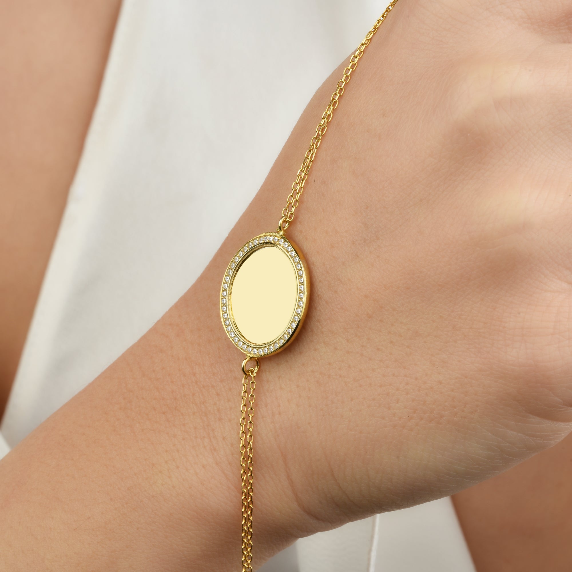 Goldene Gravur Armkette am Handgelenk – runder Anhänger mit Zirkonia, personalisierbar.