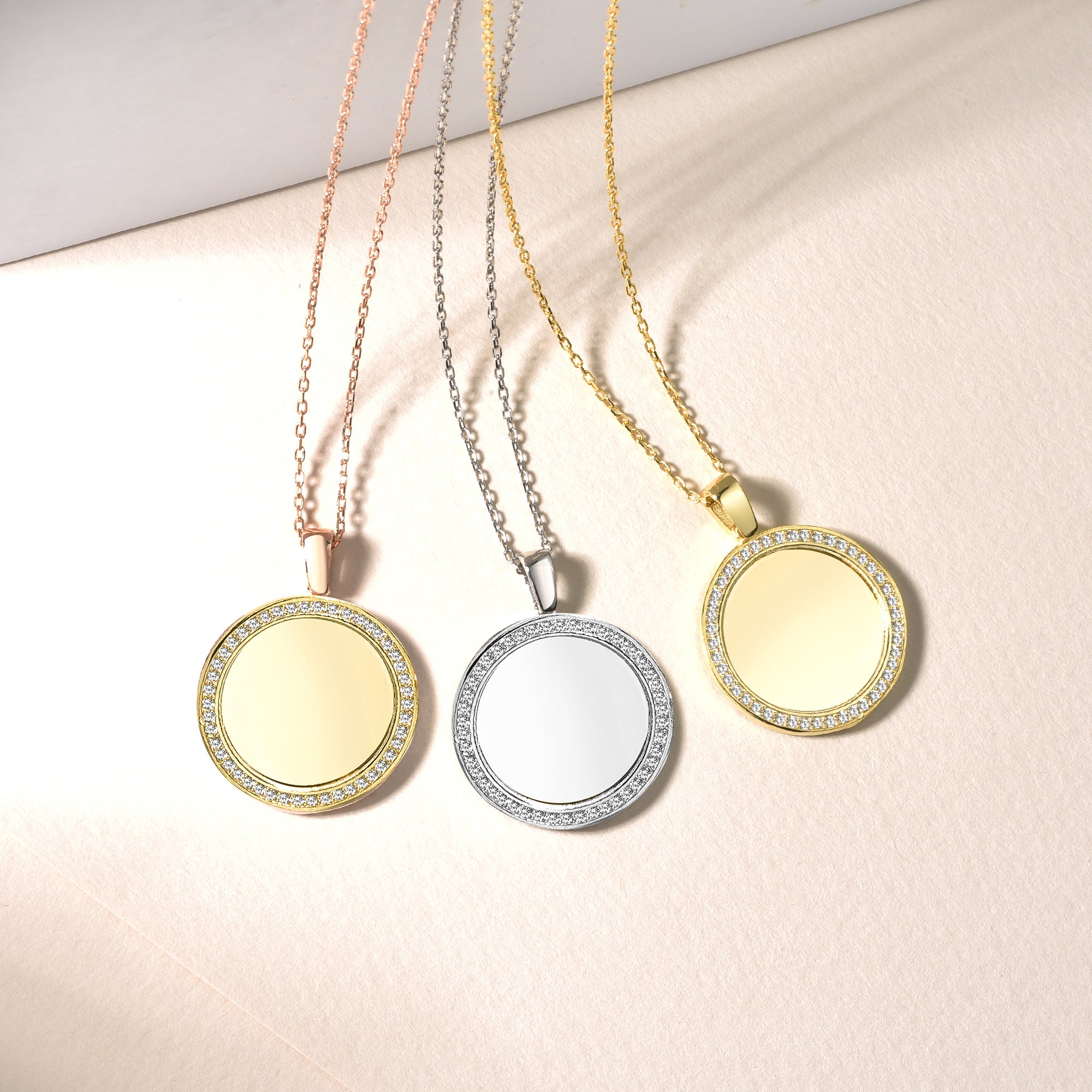 Drei Mirror Gravur Ketten in Rosé, Silber und Gold nebeneinander auf hellem Untergrund.