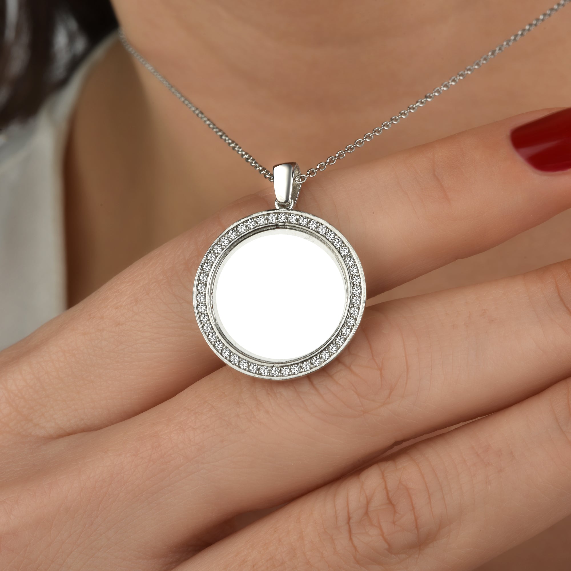 Nahaufnahme der silbernen Mirror Gravur Kette zwischen Fingern mit rotem Nagellack.