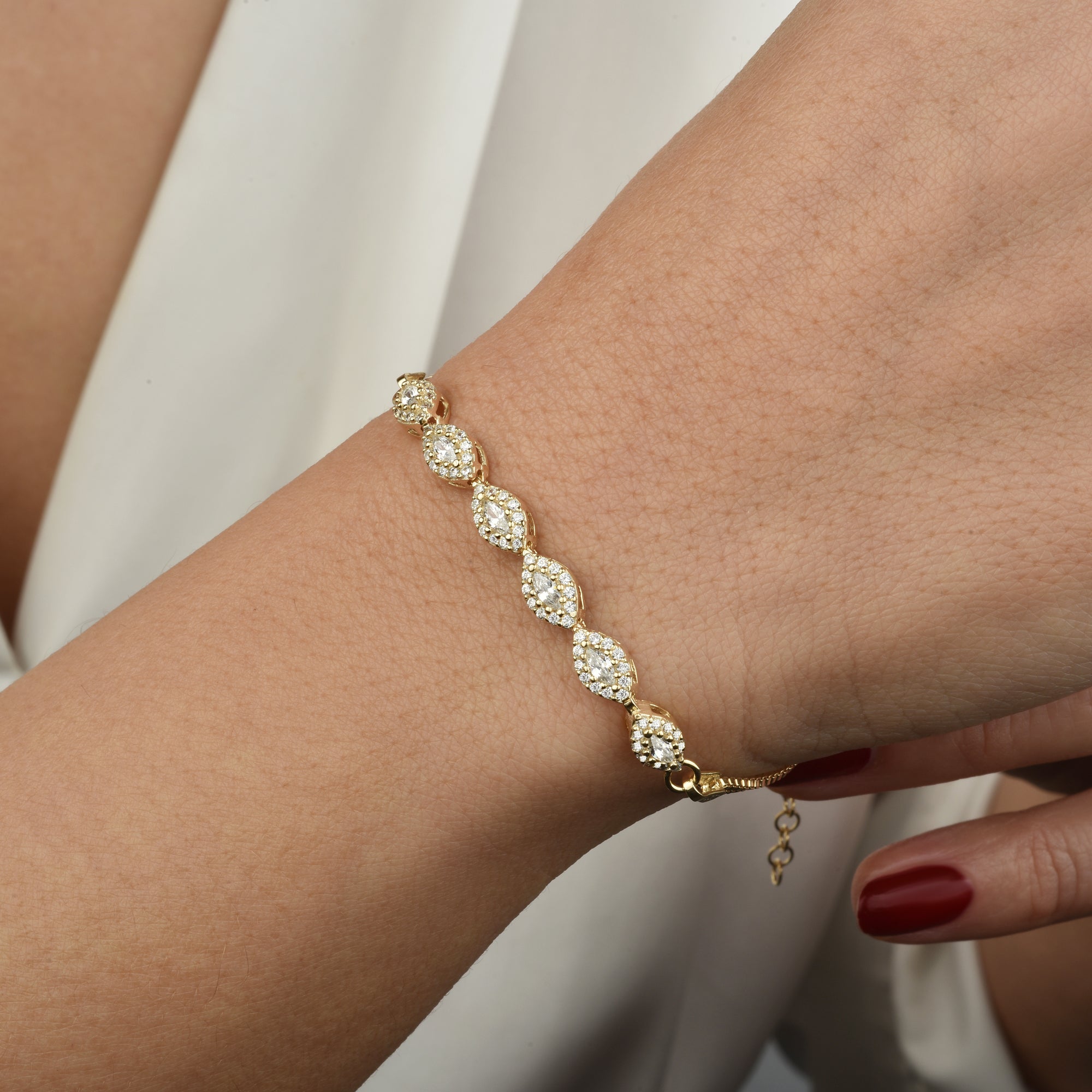 Close-up: Navet Zirkonia Armband Gold am Handgelenk, weiße Zirkonia in augenförmigen Elementen.