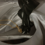 Notenschlüssel Kette Gold mit Zirkonia auf Satin und Spiegel – elegantes Produktfoto.