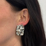 Silberne Steel Grace Ohrstecker am Ohr getragen, glänzende strukturierte Oberfläche, Close-up