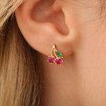 Kirsche-Ohrstecker am Ohr getragen, zartes Fruchtmotiv in Goldoptik.