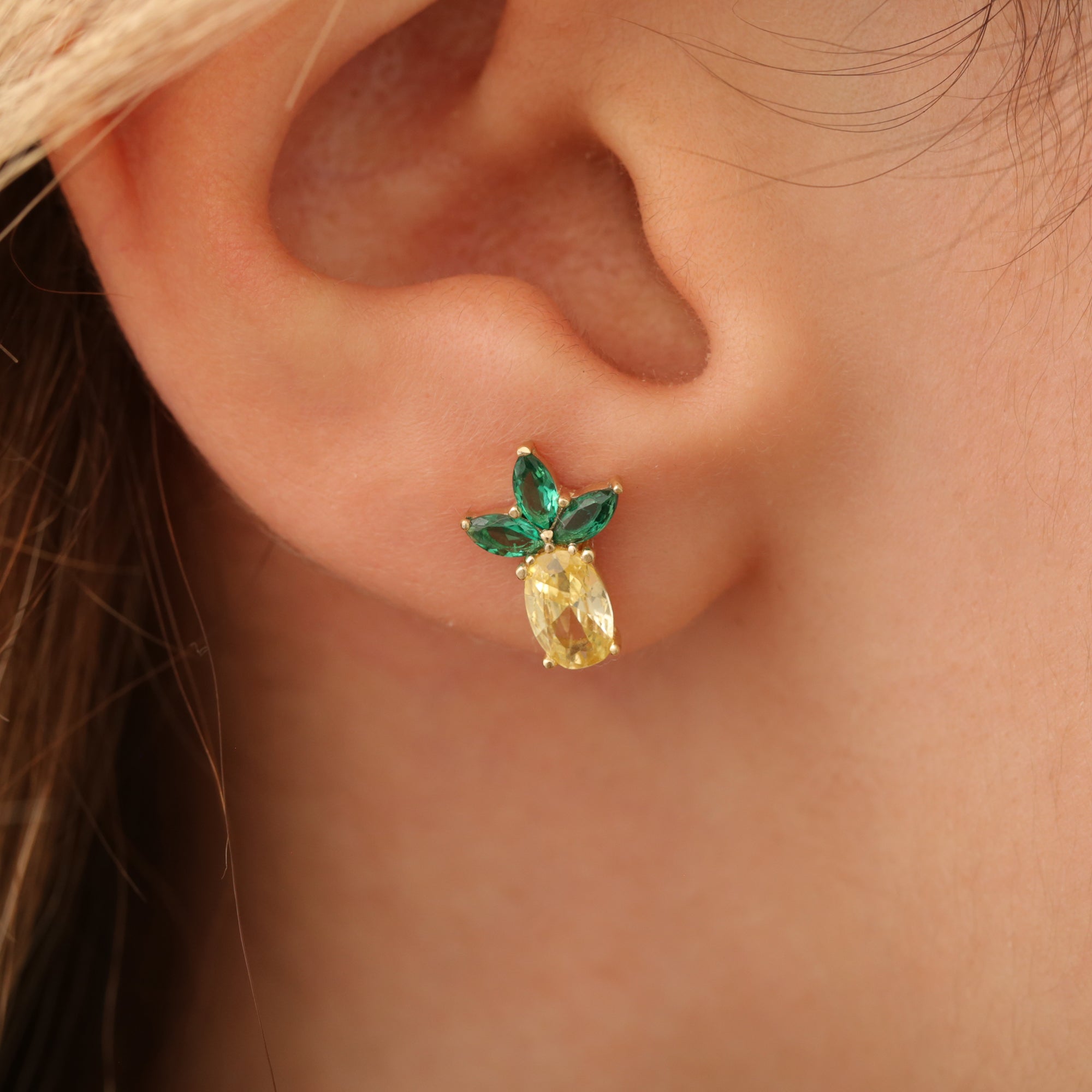 Ananas-Ohrstecker am Ohr, Stein gelb mit grünem Blatt, 14K vergoldete Fassung.