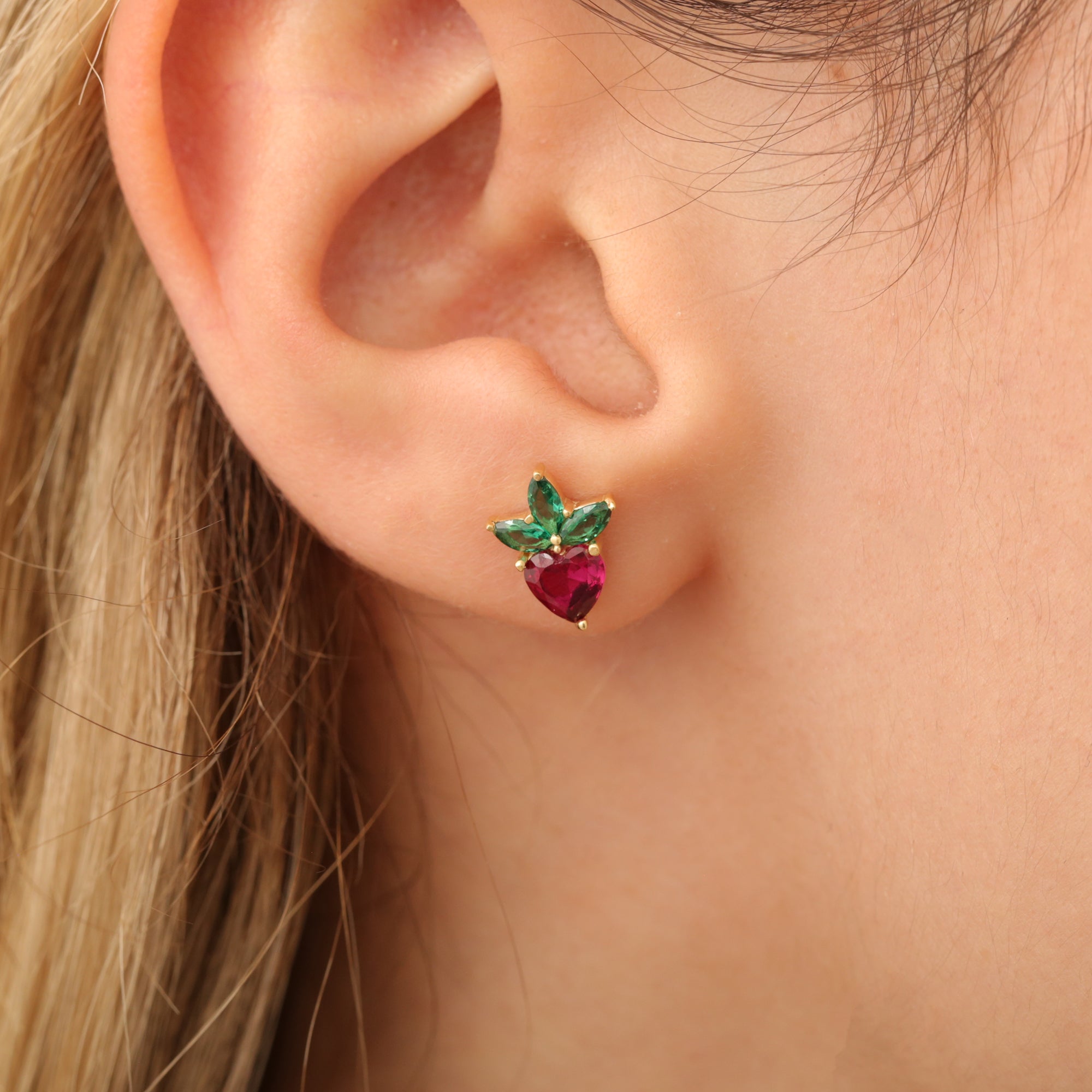 Erdbeere-Ohrstecker am Ohr, Herzstein rot mit grünem Blatt, 14K vergoldete Fassung.