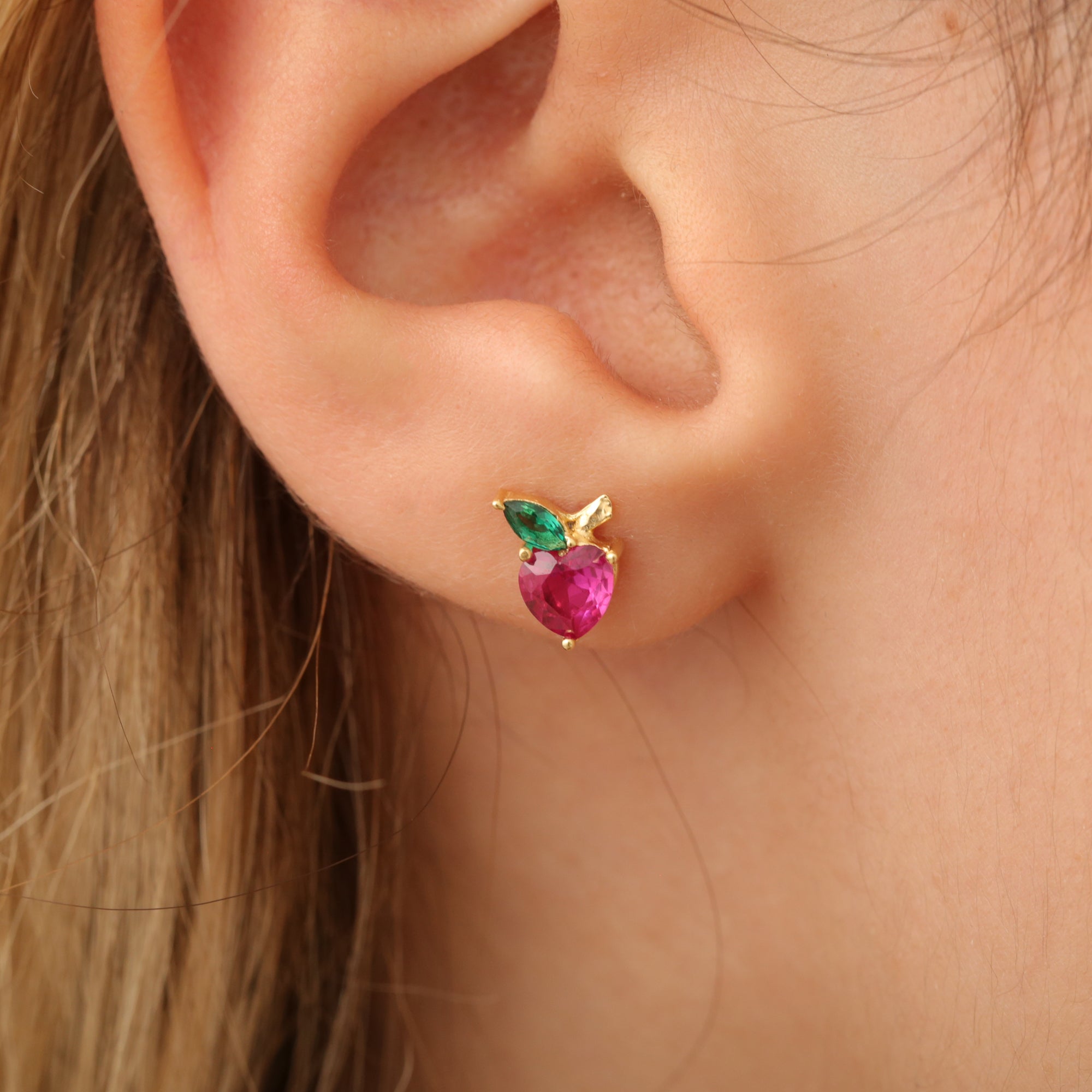 Apfel-Ohrstecker am Ohr, Herzstein rot mit grünem Blatt, 14K vergoldete Fassung.