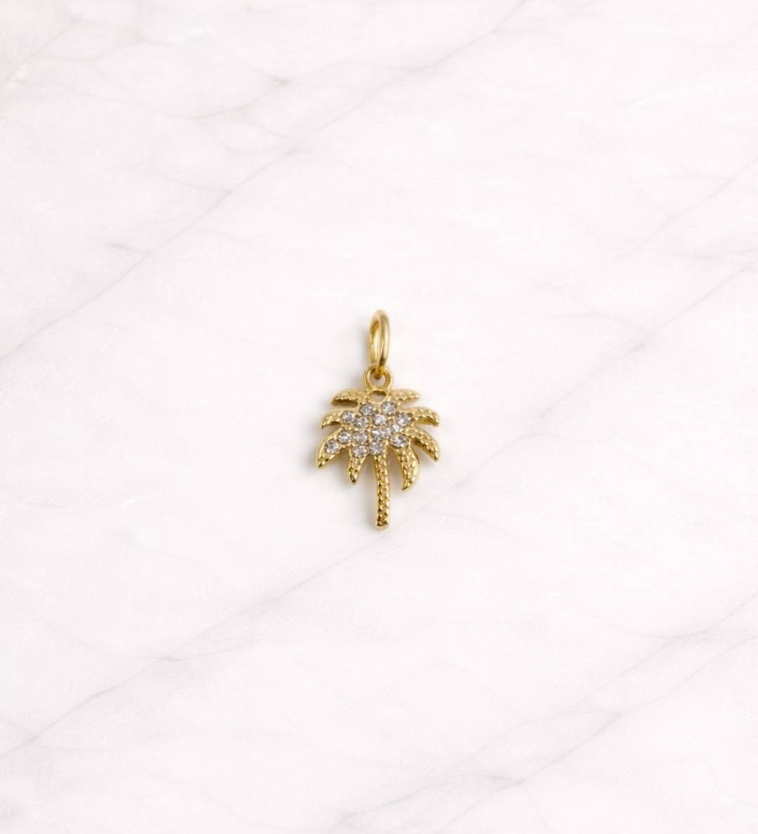 Palm Beach Charm in Gold mit Zirkonia in Palmenform auf hellem Hintergrund.