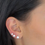 Frau trägt Pearl Balls Perlen Ohrstecker in Silber und Gold im Ohrläppchen, moderner Ear-Stacking-Look.