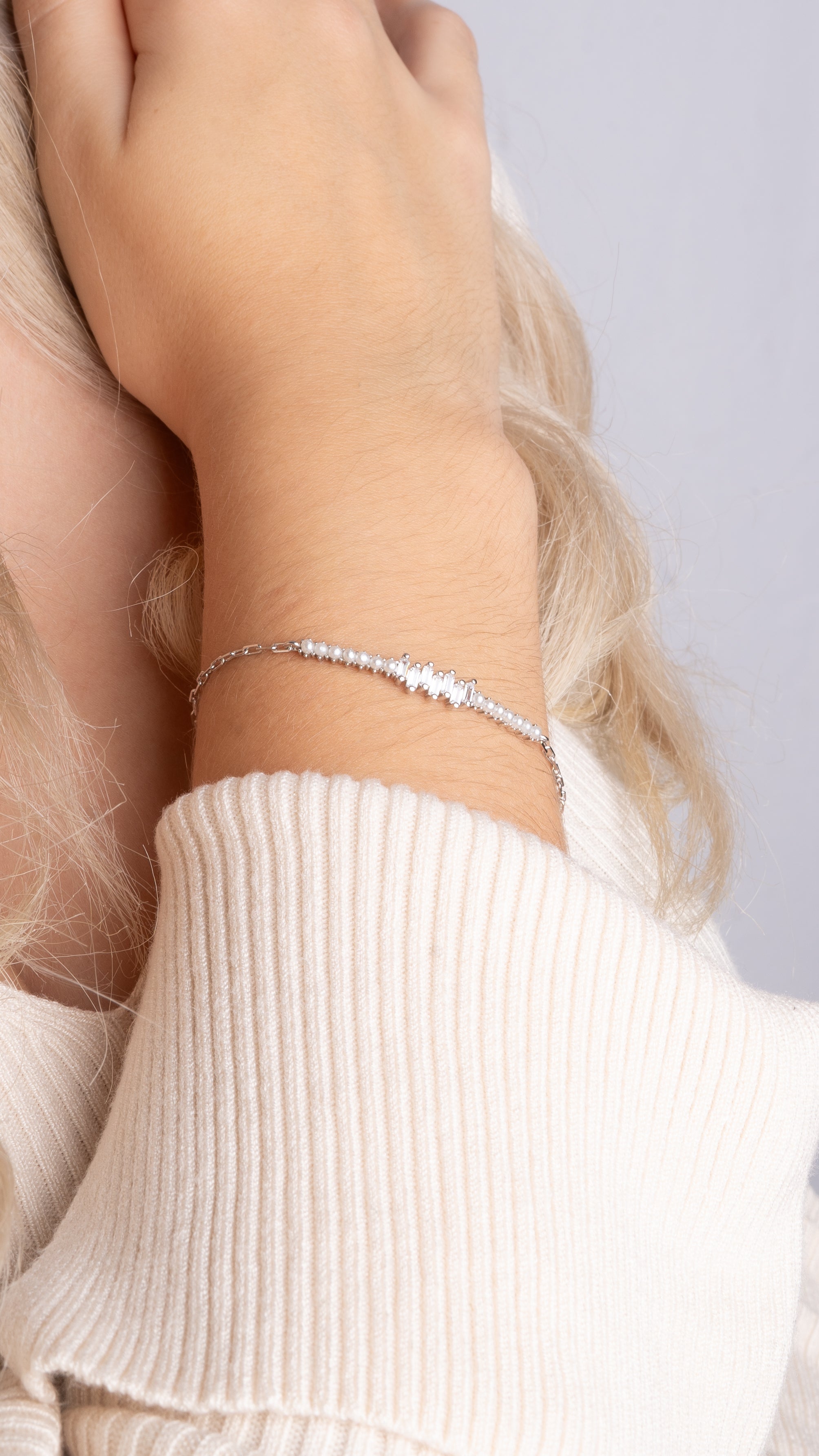 Pearl X Baguette Armkette Silber mit Perlen und Zirkonia an weiblichem Handgelenk.