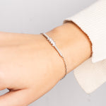 Zarte Pearl X Baguette Armkette in Silber an Handgelenk mit cremefarbenem Pullover.