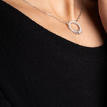 Pearl X Baguette Halskette in Silber am Hals einer Frau mit schwarzem Oberteil.