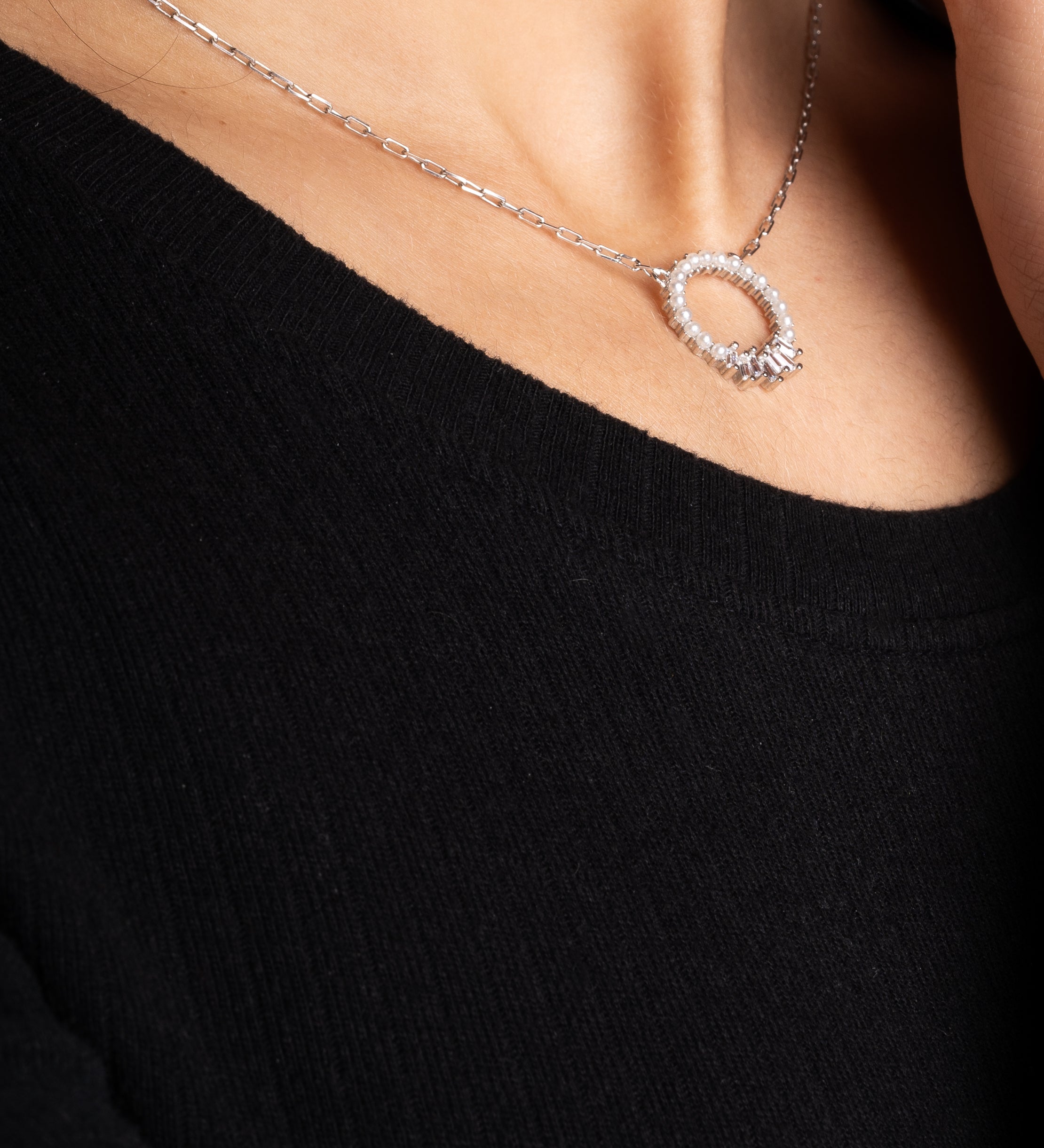 Pearl X Baguette Halskette in Silber am Hals einer Frau mit schwarzem Oberteil.