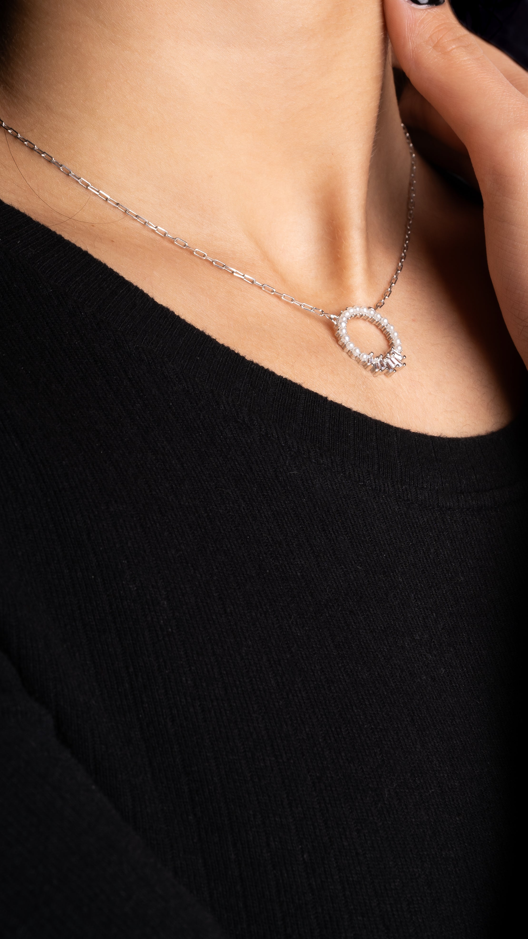 Pearl X Baguette Halskette in Silber am Hals einer Frau mit schwarzem Oberteil.