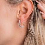 Nahaufnahme Pearl X Baguette Ohrring in Silber am Ohr einer Frau.