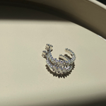 Pearl X Baguette Ohrringe in Silber mit Perlen und Zirkonia auf beigem Untergrund.