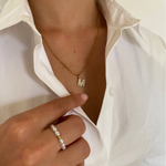 Perl Ring mit goldener Kugel an Damenhand, kombiniert mit goldener M-Halskette.