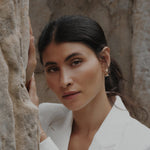 Model mit elegantem weißen Blazer trägt Perl Zirkonia Creolen in Gold am Ohr.