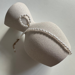 Goldenes Perlen Armband und passende Kette dekorativ auf hellem Schmuckdisplay arrangiert.