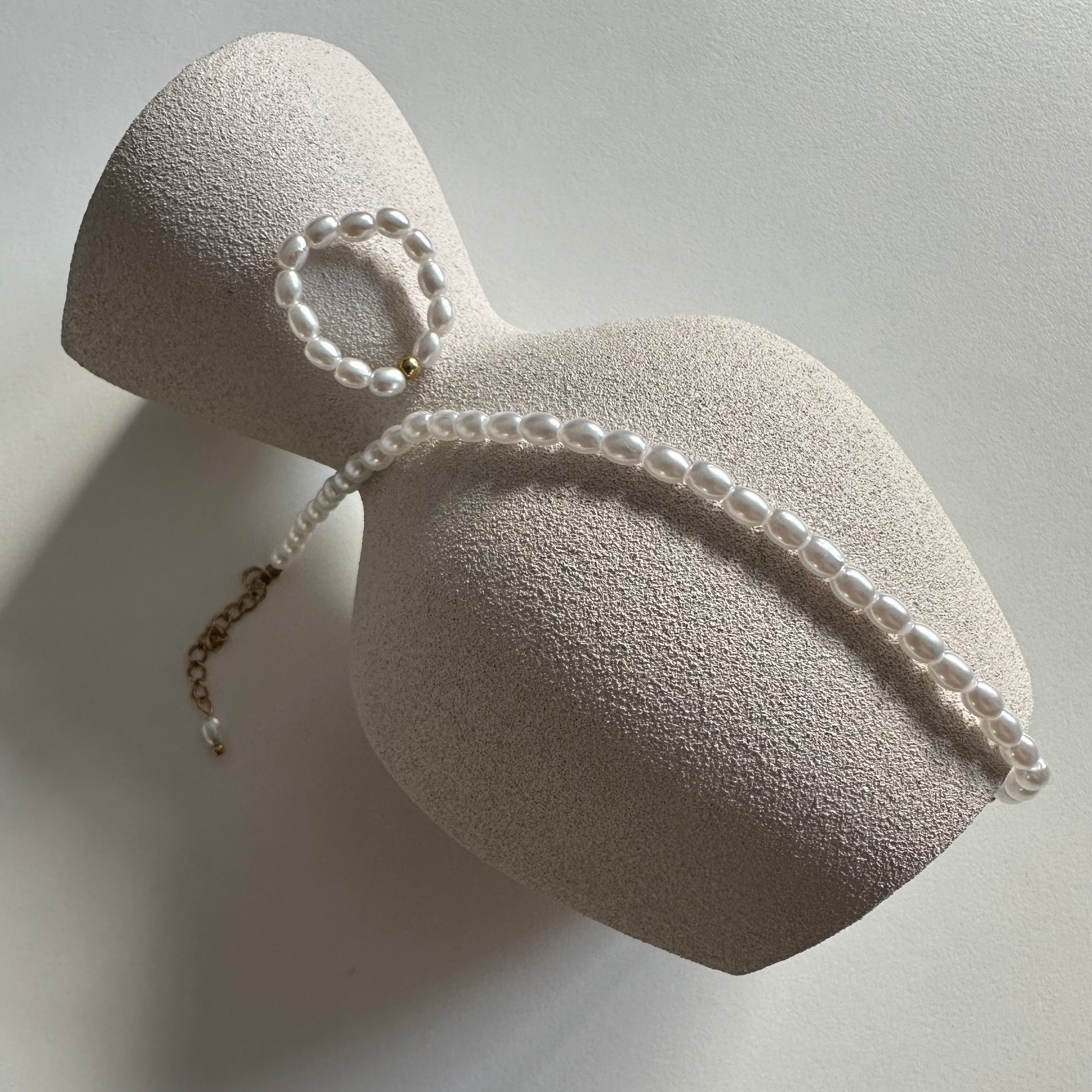 Goldenes Perlen Armband und passende Kette dekorativ auf hellem Schmuckdisplay arrangiert.