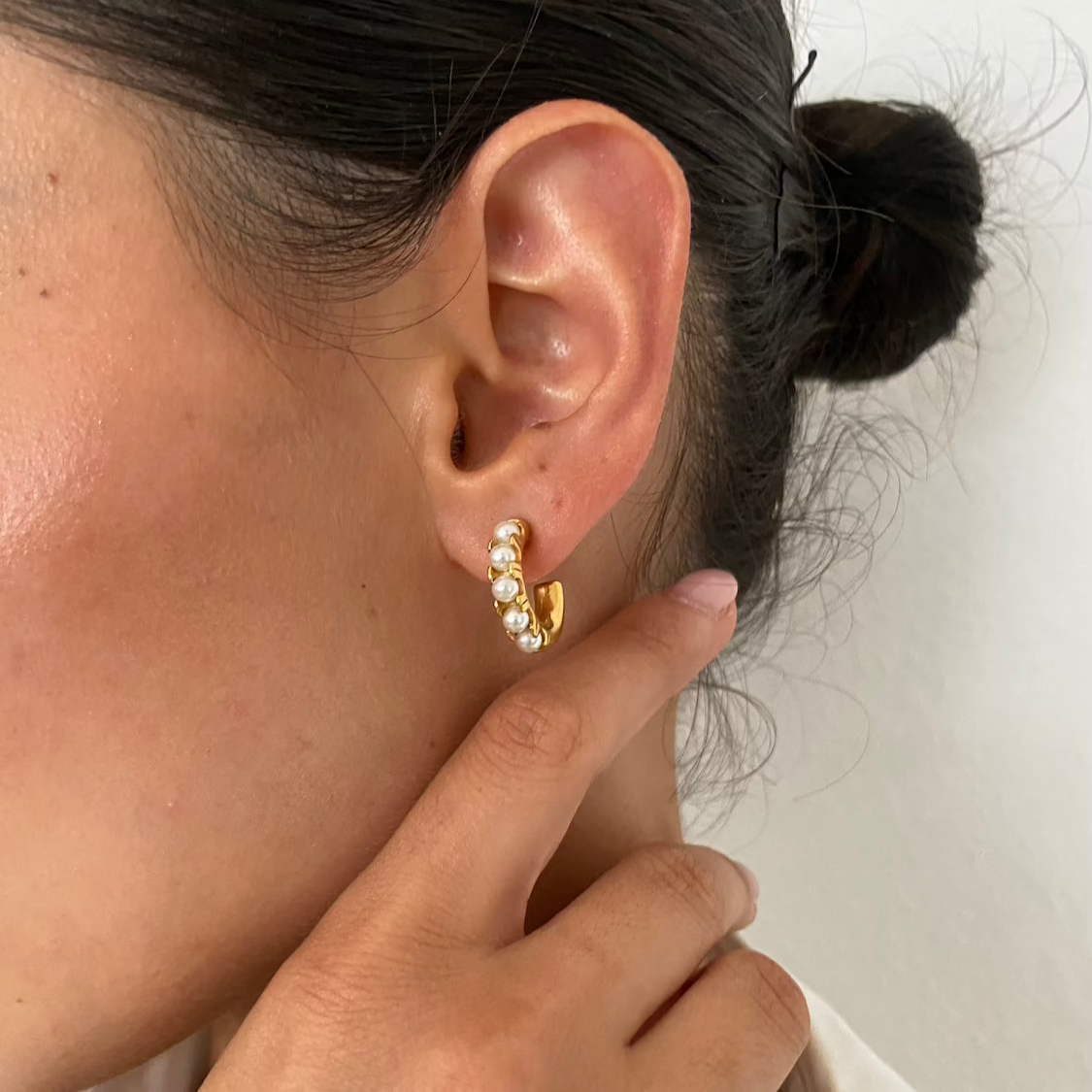 Frau trägt goldene Perlen Creolen am Ohr, Nahaufnahme mit Hand, eleganter Alltagslook Schmuck von Dkeniz.