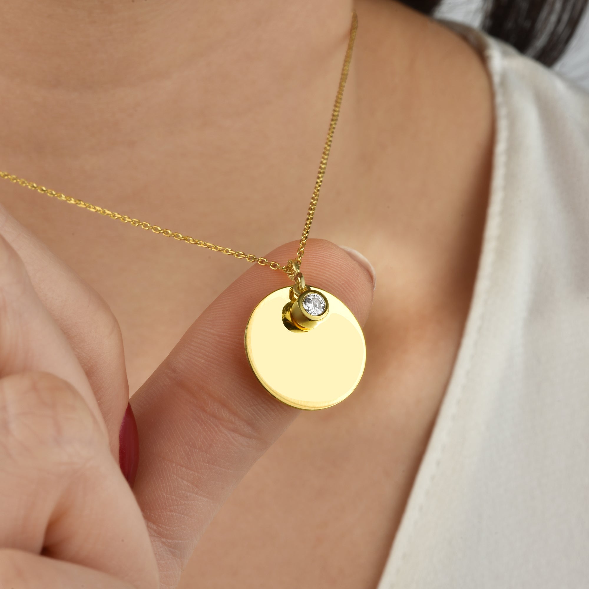 Close-up: runder Gold-Anhänger mit Zirkonia an feiner Kette – glänzend und hochwertig.