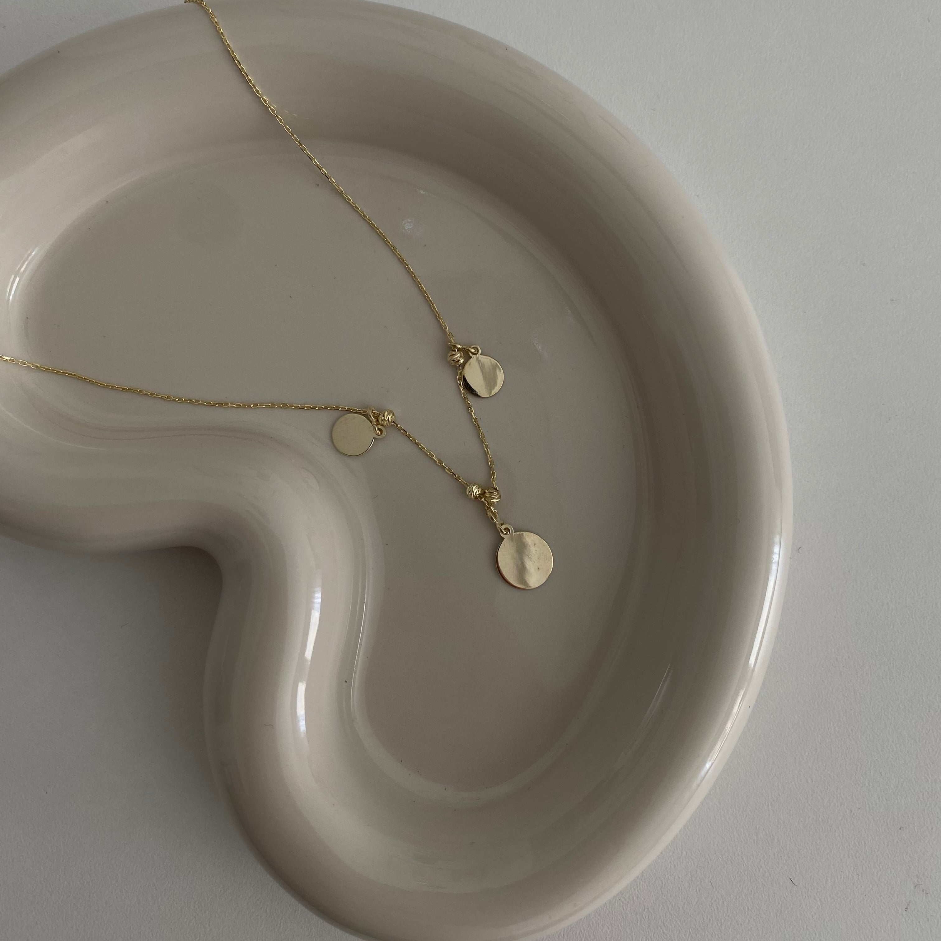 Runde Plättchen Kette Gold mit 3 Anhängern auf Schmuckschale – feine, elegante Halskette.