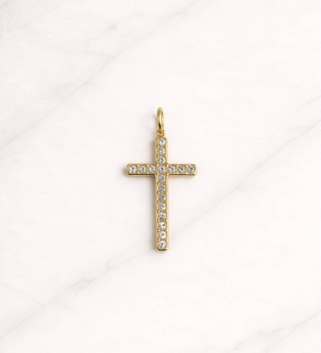 San Aurelia Kreuz Charm in Gold mit funkelnden Steinen auf hellem Hintergrund.