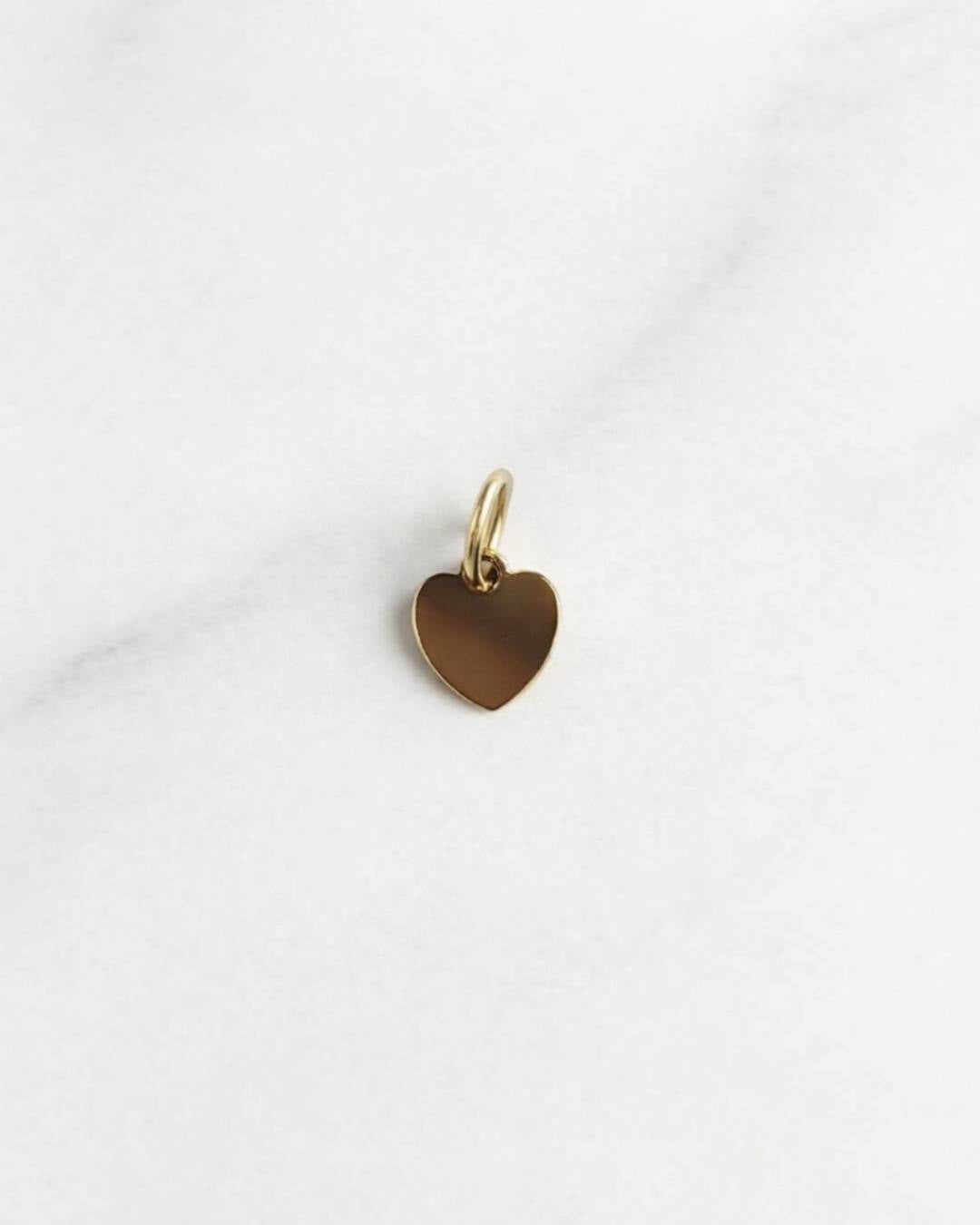 Goldener Santorini Charm in Herzform, 18K vergoldet, minimalistisch und elegant auf hellem Hintergrund.