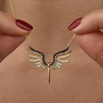 Close-up: Schutzengel Anhänger in Gold mit farbigem Zirkonia-Mix, gehalten zwischen zwei Fingern.