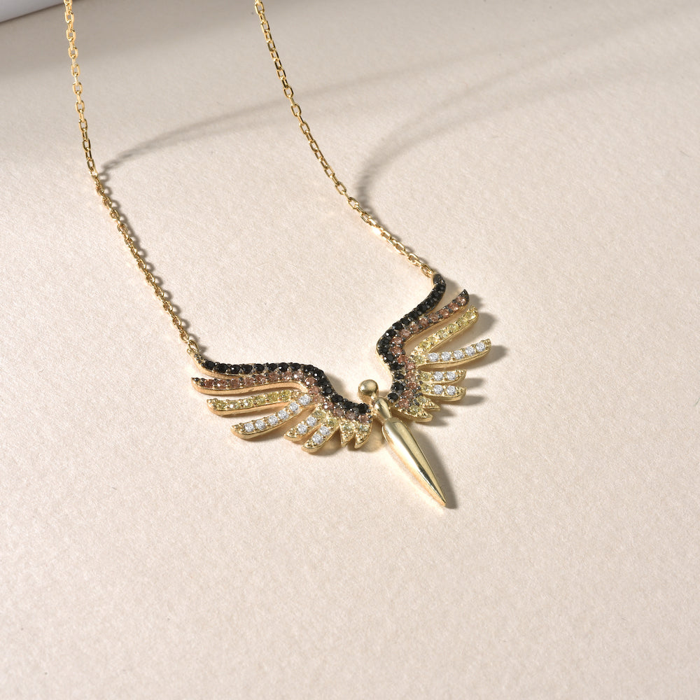 Schutzengel Kette Gold auf Stoff liegend – Detailansicht Engel-Flügel Anhänger mit Zirkonia-Mix.