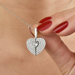 Hand mit rotem Nagellack hält funkelnden Secret Heart Anhänger in Silber.
